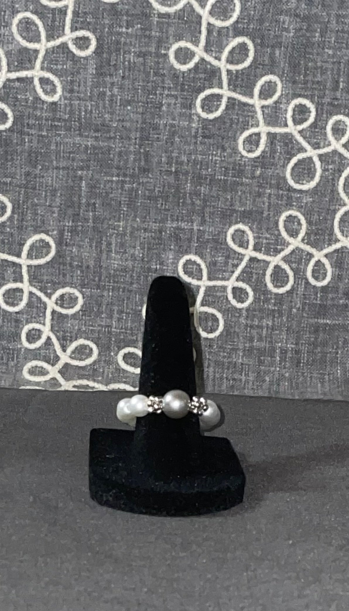Smoky Pearl Grace Ring with silver-gray glass pearl centerpiece and sparkling crystal accent beads on a black ring display